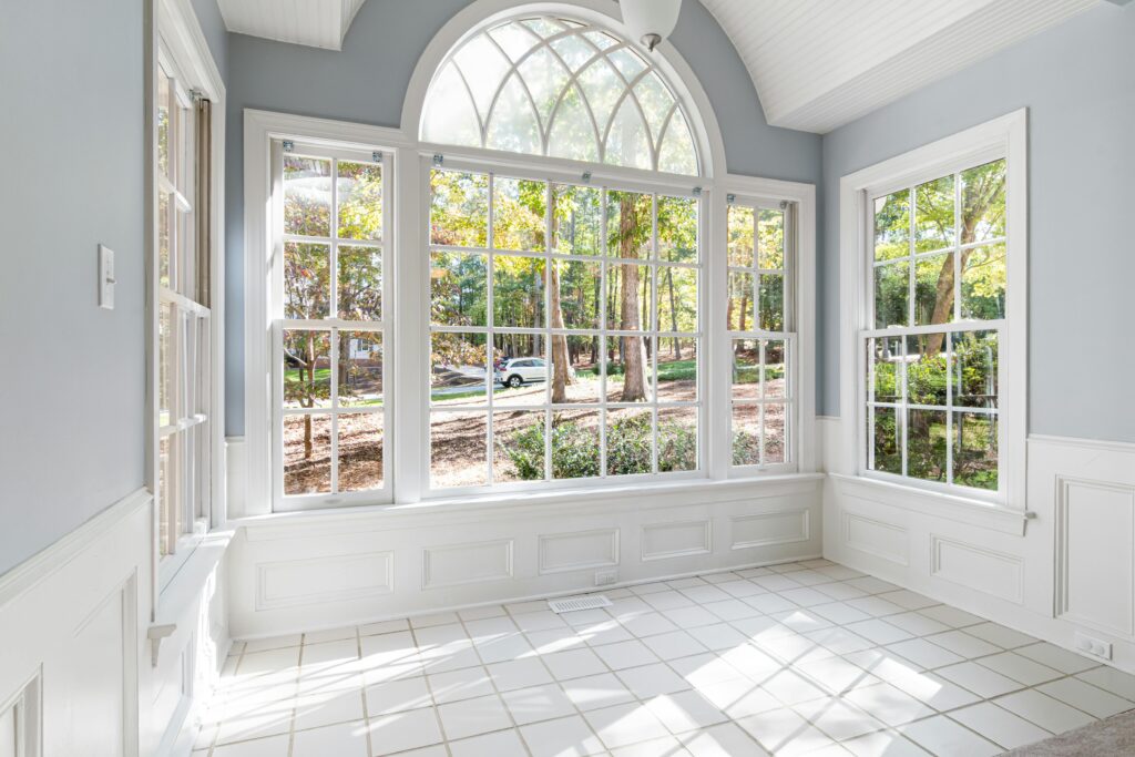 Spacious sunroom with large glass windows offering an outdoor view.